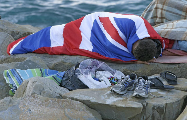 A migrant sleeps on the rocky beach at the Franco-Italian border near Menton, southeastern France Wednesday, June 17, 2015. European Union nations failed to bridge differences Tuesday over an emergency plan to share the burden of the thousands of refugees crossing the Mediterranean Sea, while on the French-Italian border, police in riot gear forcibly removed dozens of migrants. (AP Photo/Lionel Cironneau)