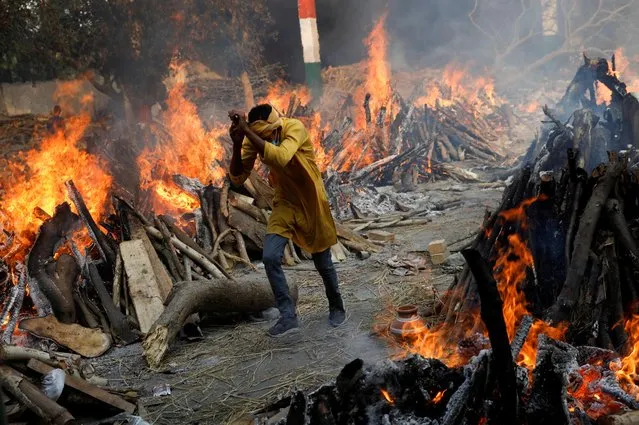 A man runs past the burning funeral pyres of those who died from the coronavirus disease (COVID-19), during a mass cremation, at a crematorium in New Delhi, India on April 26, 2021. (Photo by Adnan Abidi/Reuters)