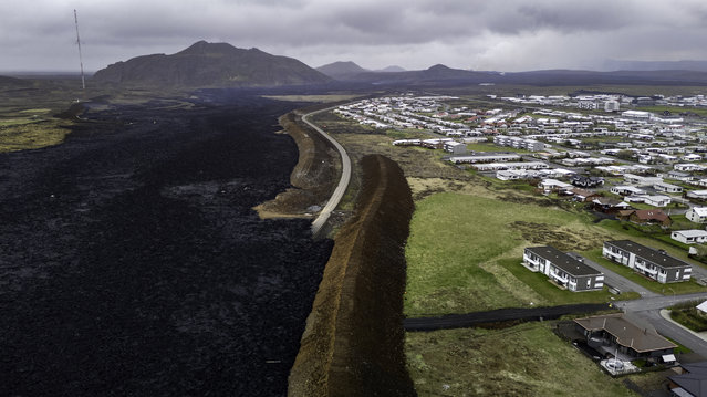 Seen from an aerial view, earthen berms protect the town of Gridavik from lava after a volcano erupted for the fifth time since December on the Reykjanes peninsula on May 30, 2024 near Grindavik, Iceland. The volcano began flowing anew the day before, cutting electricity to Grindavik and forcing the evacuation of hundreds of guests at the nearby Blue Lagoon geothermal spa. (Photo by John Moore/Getty Images)