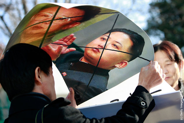 North Korean defectors hold defaced posters of North Korea leader Kim Jong-Il and his son Jong-un as they participate in a anti-North Korea protest