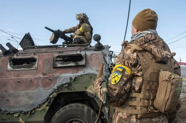 Ukrainian soldiers inspect a damaged military vehicle after fighting in Kharkiv, Ukraine, Sunday, February 27, 2022. (Photo by Marienko Andrew/AP Photo)