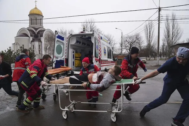 Ambulance paramedics move an injured man on a stretcher, wounded by shelling in a residential area, at a maternity hospital converted into a medical ward and used as a bomb shelter in Mariupol, Ukraine, Tuesday, March 1, 2022. (Photo by Evgeniy Maloletka/AP Photo)