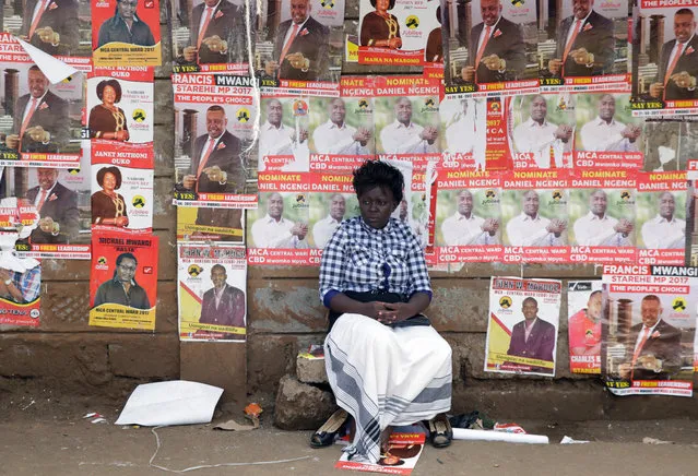 A woman sits in front of campaign posters as she waits to cast her ballot, during the Jubilee Party primary elections, at a polling centre in Nairobi, Kenya April 26, 2017. (Photo by Thomas Mukoya/Reuters)