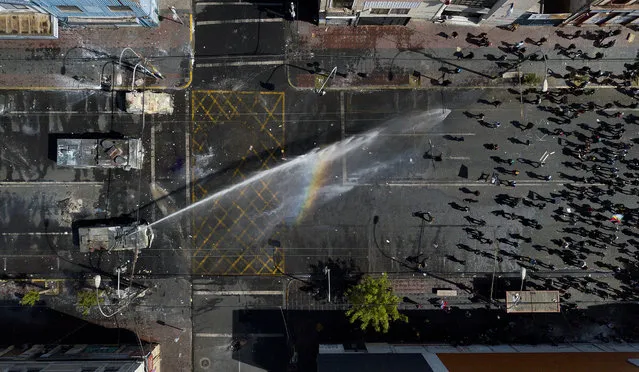 A police water cannon sprays anti-government demonstrators in Valparaiso, Chile, Saturday, October 26, 2019. Clashes broke out Saturday as demonstrators returned to the streets, dissatisfied with economic concessions announced by the government in a bid to curb a week of deadly violence. (Photo by Matias Delacroix/AP Photo)