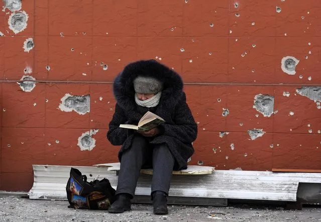 A local resident reads a book near a building damaged in the course of Ukraine-Russia conflict in the southern port city of Mariupol, Ukraine on April 3, 2022. (Photo by Reuters/Stringer)