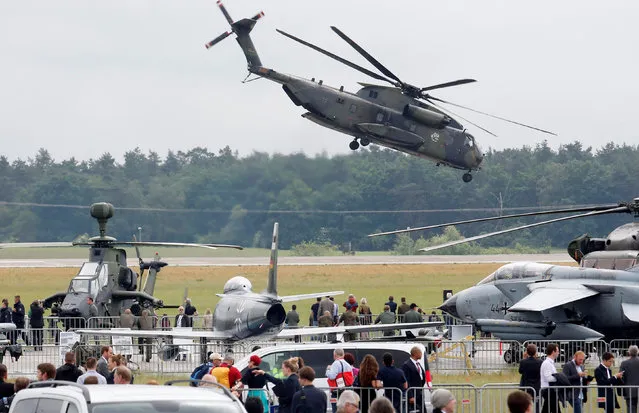 Visitors walk at the ILA Berlin Air Show as a German armed forces Bundeswehr CH-53 helicopter takes off in Schoenefeld, south of Berlin, Germany, June 1, 2016. (Photo by Fabrizio Bensch/Reuters)