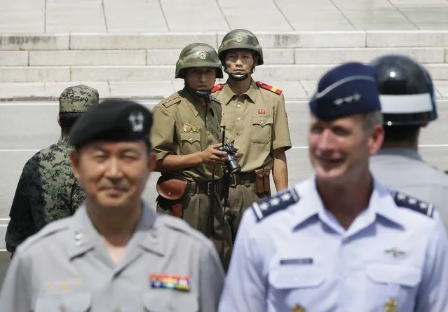 North Korean army soldiers watch the south side as United Nations Command's Deputy Commander and deputy commander of USFK Seventh Air Force commander Lt. Gen. Terrence J. O'Shaughnessy (R) and senior member United Nations command military armistice commission Chang Kwang-hyun, pose for a souvenir photo after attending a ceremony to commemorate the 62nd anniversary of the Korean War Armistice Agreement. (Photo by Ahn Young-joon/Reuters)