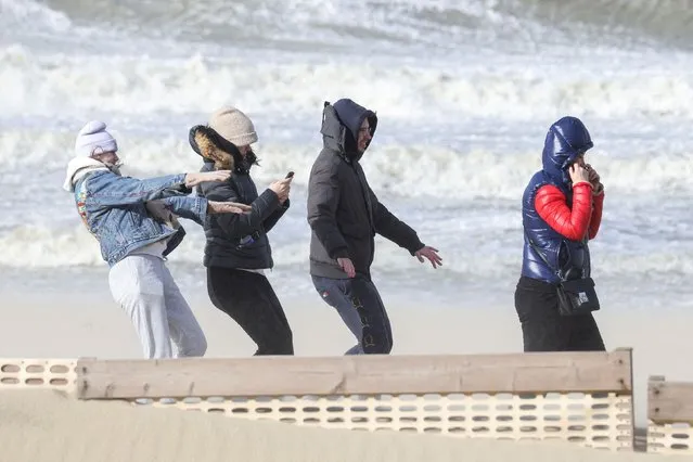 People walk as waves break on the beach in the wake of Storm Eunice in Blankenberge, Belgium, February 18, 2022. (Photo by Yves Herman/Reuters)
