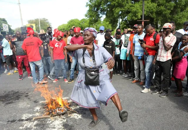 A woman gestures around a fire set during a voodoo ceremony ahead of protests demanding that the government of Prime Minister Ariel Henry do more to address gang violence including constant kidnappings, in Port-au-Prince, Haiti on March 29, 2022. (Photo by Ralph Tedy Erol/Reuters)