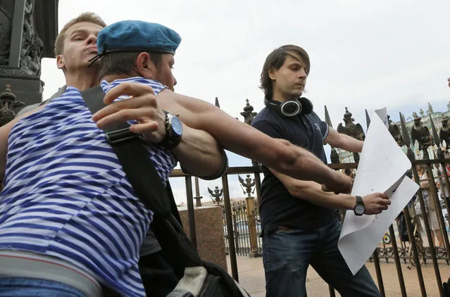 A former paratrooper celebrating Paratroopers Day, left, attempts to take away a broadsheet of a gay right activist who is taking part in a protesting picket at Dvortsovaya (Palace) Square in St.Petersburg, Russia, Sunday, August 2, 2015. (Photo by Dmitry Lovetsky/AP Photo)