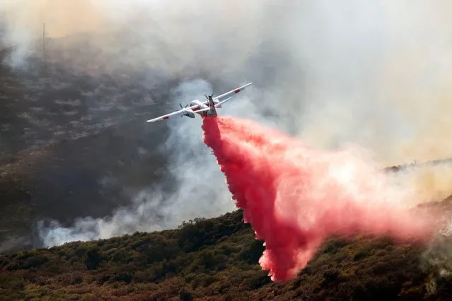A fire plane drops red fire retardant the Coastal wildfire in Laguna Niguel, California on May 11, 2022. A wind-driven wildfire that broke out Wednesday in brush near Laguna Niguel grew to 200 acres, burned about 20 homes and prompted the evacuation of nearby residences and a luxury resort, fire officials said. (Photo by Ruaridh Stewart/ZUMA Press Wire/Alamy Live News)