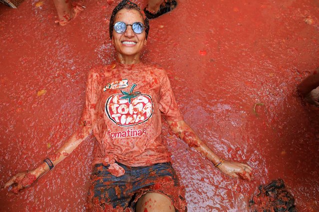 A participant lies in tomato pulp, as people attend the annual food fight festival “La Tomatina” in Bunol, near Valencia, Spain on August 28, 2024. (Photo by Eva Manez/Reuters)