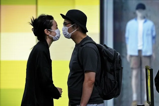 A couple wearing face masks move in closer to kiss as they line up for their COVID-19 tests at a testing facility near a shopping mall where most shops have ordered to closed as part of COVID-19 controls in Beijing, Monday, June 13, 2022. (Photo by Andy Wong/AP Photo)