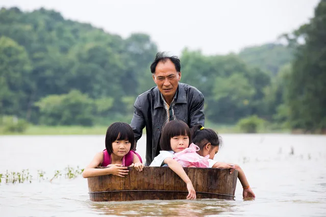 A man pushes a tub carrying children as he gets them back home after school at a flooded area in Duchang, Jiangxi Province, China, June 27, 2016. (Photo by Reuters/Stringer)
