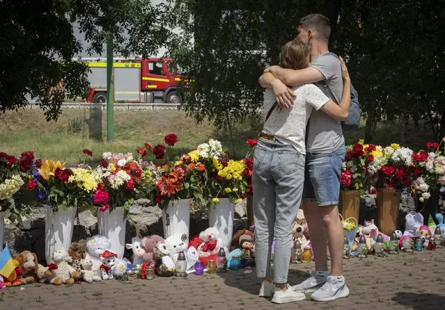 People lay flowers to pay the last respect to victims of the Russian rocket attack at a shopping center in Kremenchuk, Ukraine, Wednesday, June 29, 2022. (Photo by Efrem Lukatsky/AP Photo)