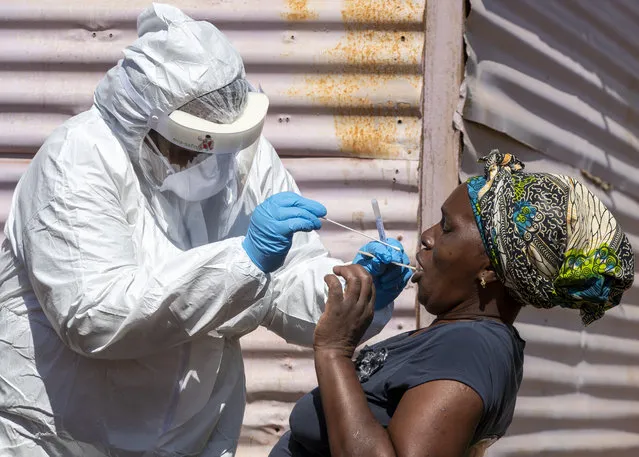 A woman opens her mouth for the heath worker to collect a sample for coronavirus testing during the screening and testing campaign aimed to combat the spread of COVID-19 at Lenasia South, south Johannesburg, South Africa, Tuesday, April 21, 2020. (Photo by Themba Hadebe/AP Photo)