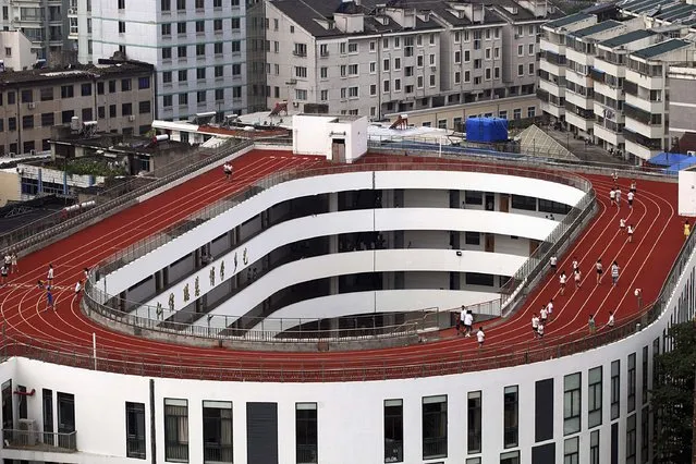 Students exercise on a track on the rooftop of a campus building, at a primary school in Tiantai county, Zhejiang province September 1, 2014. The school built this 200-metre track on top of a four-storey building due to insufficient space of the campus. According to local media, this design project has been submitted to compete in the 14th International Architecture Exhibition which is ongoing in Venice, Italy. (Photo by Reuters/China Daily)