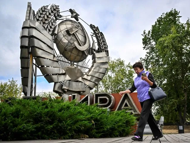 A woman walks past an emblem of the USSR which was removed from Leninsky avenue after the collapse of the Soviet Union in 1991, displayed at the Modern History Sculpture Museum park in Moscow on August 31, 2022. Mikhail Gorbachev, who changed the course of history by triggering the demise of the Soviet Union and was one of the great figures of the 20th century, died in Moscow on August 30, 2022 aged 91. (Photo by Alexander Nemenov/AFP Photo)