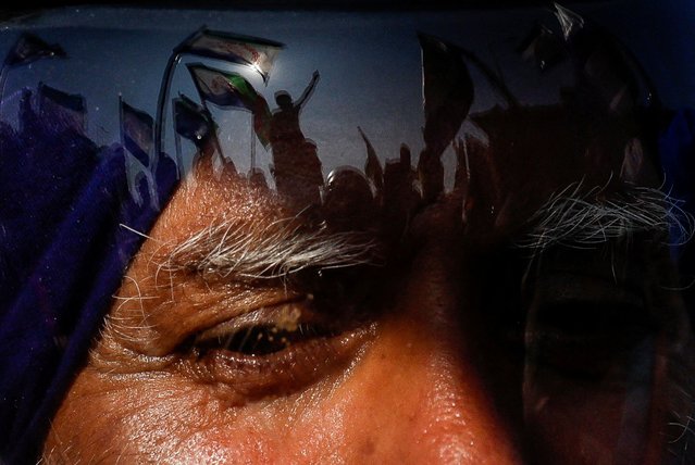 Protesters are reflected on a man's helmet, as farmers march towards New Delhi to press for better crop prices promised to them in 2021, at the Shambhu barrier, a border crossing between Punjab and Haryana states, India, on December 6, 2024. (Photo by Anushree Fadnavis/Reuters)