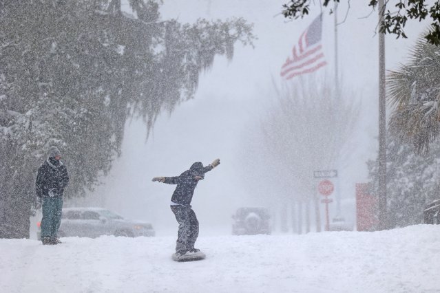Julian Zachari sleds as his friend Nathaniel Seipel looks on in City Park during a snow storm on January 21, 2025 in New Orleans, Louisiana. A winter storm brought rare snowfall to the city shutting down schools and businesses and drawing out locals, many of whom had never seen snow before. (Photo by Michael DeMocker/Getty Images)