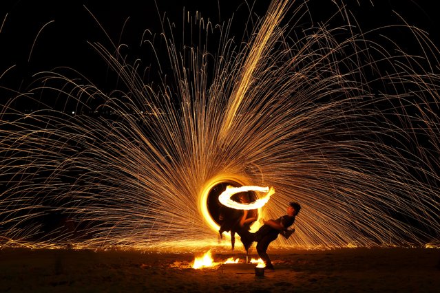 Malay artists perform a fire sparkling performance on a beach side during the Christmas festive season and school holidays on Pangkor Island, Malaysia, Thursday, December 26, 2024. (Photo by Andy Wong/AP Photo)