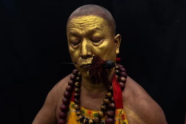 A medium man with his mouth pierced is portrayed while in trance during the Ban Tha Rue Shrine procession amidst celebrations of the annual vegetarian festival, observed by Taoist devotees from the Thai-Chinese community in the ninth lunar month of the Chinese calendar, in Phuket Town, Thailand on September 30, 2022. (Photo by Jorge Silva/Reuters)