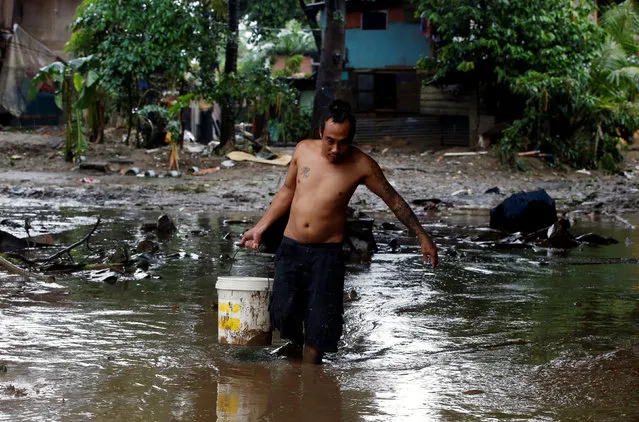 A resident carries a bucket containing drinking water as he walks on mud brought by flooding from monsoon rains in San Mateo, Rizal, Philippines, August 14, 2016. (Photo by Erik De Castro/Reuters)