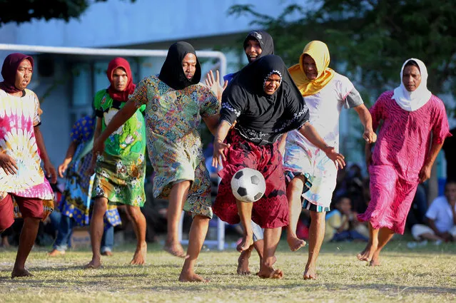 In this photograph taken on August 20, 2016, Acehnese men, dressed in woman's clothing for fooling around, play a game of football to mark the 71st Indonesian Independence Day in Banda Aceh. Indonesia celebrated its 71st Independence Day by holding many traditional and unique games, including men playing football in women's clothing as their obstacle. (Photo by Chaideer Mahyuddin/AFP Photo)