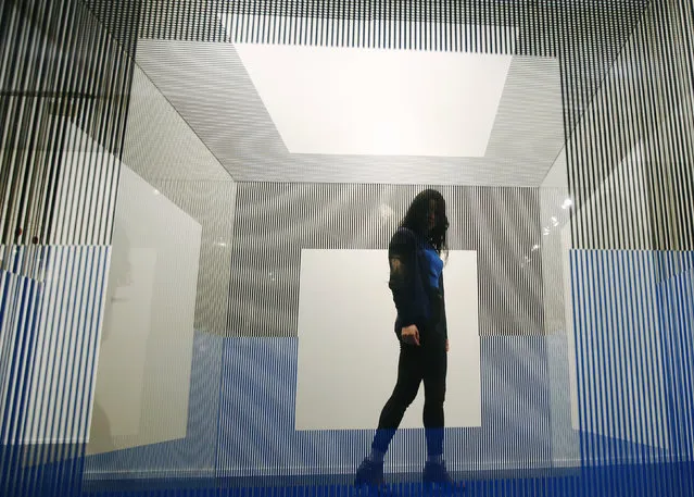 A visitor poses with artist Jesus R. Soto's artwork “Cubo de Roma” at the Frieze Masters in London, October 14, 2014. (Photo by Luke MacGregor/Reuters)