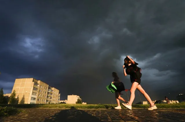 Girls brave a strong wind as storm clouds roll above the the town of Novogrudok, 150 km (93 miles) west of Minsk, Belarus, Thursday, June 18, 2020, minutes before heavy rain engulfed the city. (Photo by Sergei Grits/AP Photo)