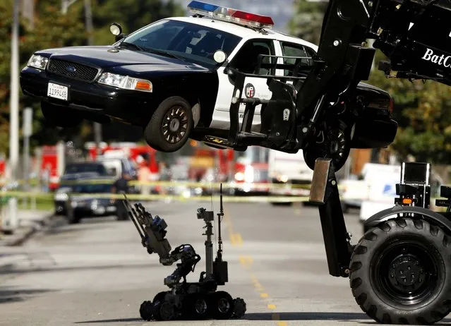 Los Angeles Police Department Bomb Squad members take a closer look at the underside of an LAPD patrol car after they received a call that a bomb had been planted in the unit on Harvard Boulevard, December 18, 2012.. After lifting the car into the air by one robotic device called a Bat Cat, another robotic device inspected the vehicle. (Photo by Mark Boster/Los Angeles Times)