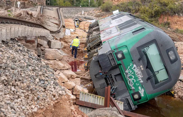 A worker inspect an wagon after it overturned due to the damages caused by heavy rains in a track connecting the towns of Floresta and Vianixa, in Lleida, Catalonia, northeastern Spain, 24 October 2019. Rescue units continue searching five people who are missing since the heavy rainfalls and flood that hit the region in the evening of last 22 October and early morning 23 October. (Photo by Adrian Ropero/EPA/EFE)