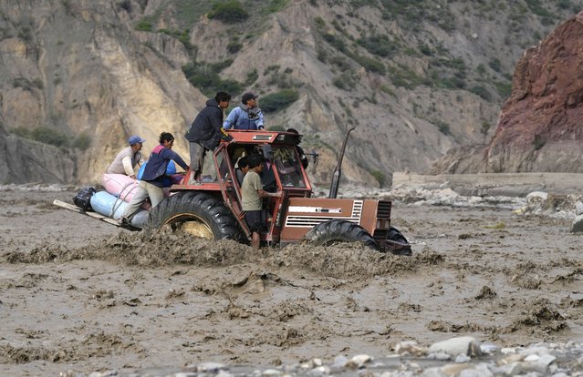 A tractor transporting farmers' produce to sell at the markets, crosses the La Paz river inundated by a mudslide due to persistent rains, in El Penol, Bolivia, Friday, February 23, 2024. (Photo by Juan Karita/AP Photo)