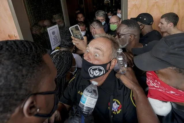 Police try to secure the public safety building from protesters Monday, August 24, 2020, in Kenosha, Wis. Wisconsin Gov. Tony Evers has summoned the National Guard to head off another round of violent protests after the police shooting of a Black man under murky circumstances turned Kenosha into the nation’s latest flashpoint city in a summer of racial unrest. (Photo by Morry Gash/AP Photo)