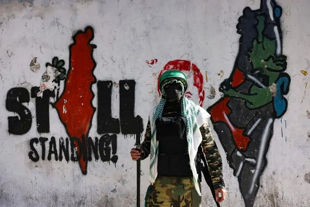 A masked supporter of the Hamas movement, takes part in a rally in the West Bank village of Beit Omar, to mark the 35th anniversary of the Palestinian militant group, on December 16, 2022. (Photo by Hazem Bader/AFP Photo)