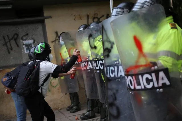 People spray paint on police riot shields as they protest outside a police station after a man, who was detained for violating social distancing rules, died from being repeatedly shocked with a stun gun by officers, according to authorities, in Bogota, Colombia on September 10, 2020. (Photo by Luisa Gonzalez/Reuters)