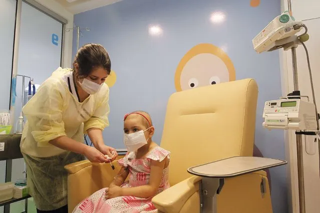 Alexandra Munoz, 5, who lost her hair due to chemotherapy to treat a malignant brain tumor, undergoes a session of treatment with the help of a nurse in the cancer ward of the Luis Calvo Mackenna Hospital in Santiago, October 20, 2014. (Photo by Rodrigo Garrido/Reuters)