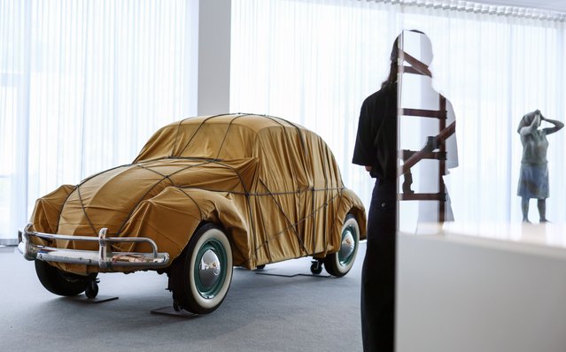 A woman stands before the “Wrapped 1961 Volkswagen Beetle Saloon” by artists Christo and Jeanne-Claude, at the Neue Nationalgalerie in Berlin, Germany, 11 June 2025. The artwork is showcased to mark the 30th anniversary of the artists' “Wrapped Reichstag”. (Photo by Hannibal Hanschke/EPA)