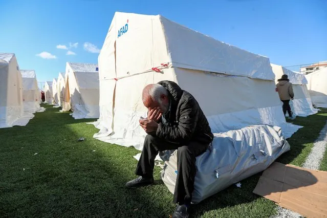 A man reacts while sitting outside a tent of a temporary accommodation centre erected on a football pitch to support people affected by a devastating earthquake in Gaziantep, Turkey on February 11, 2023. (Photo by Irakli Gedenidze/Reuters)