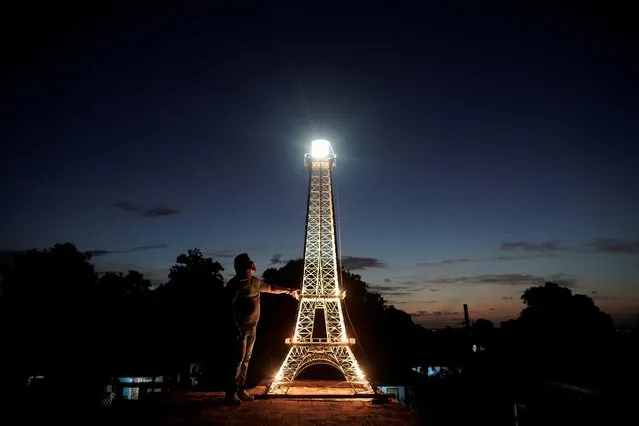 Jorge Enrique Salgado poses for a photo beside a replica of the Eiffel Tower he built on the roof of his home in Havana, Cuba, August 7, 2020. (Photo by Alexandre Meneghini/Reuters)