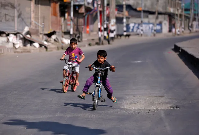 Kashmiri boys ride their bicycles in a deserted road during a curfew in downtown Srinagar, India September 23, 2016. (Photo by Danish Ismail/Reuters)