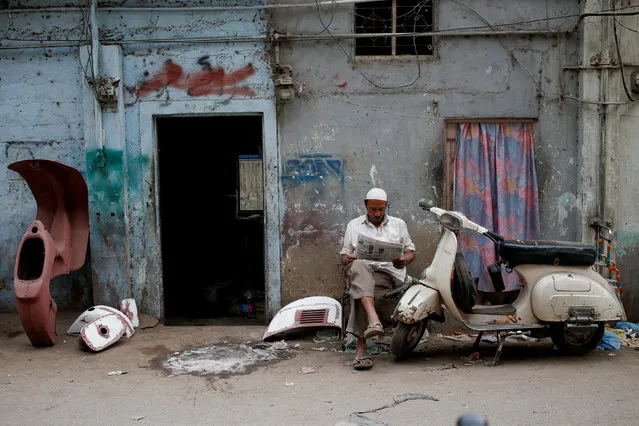 Amin, who paints repaired Vespa scooter parts, reads a newspaper outside his workshop in Karachi, Pakistan February 28, 2018. (Photo by Akhtar Soomro/Reuters)