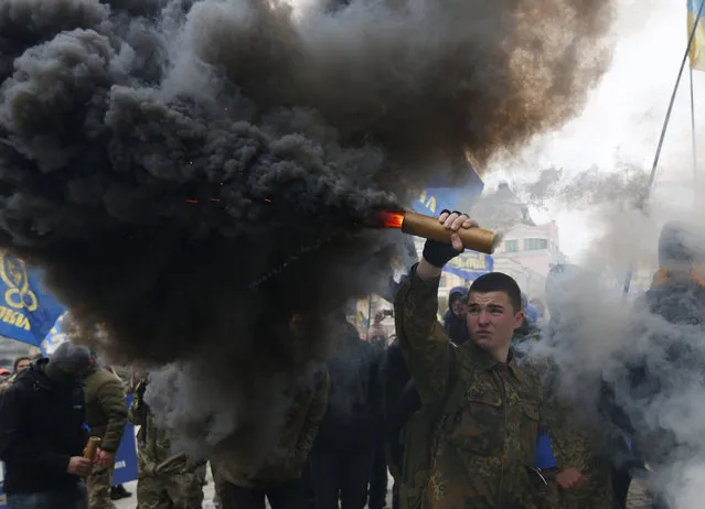 Members of the nationalist movement Svoboda (Freedom) are shrouded in smoke from flares as they march marking the 74th anniversary of the Ukrainian Insurgent Army in Kiev, Ukraine, Friday, October 14, 2016. Ukraine celebrates the Day of Defenders of Ukraine. (Photo by Sergei Chuzavkov/AP Photo)