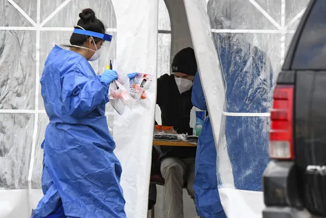 A nurse walks COVID-19 tests back to the tent at the free COVID-19 testing site on Monday, November 23, 2020 in Glenwood Springs, Colo. (Photo by Chelsea Self/Glenwood Springs Post Independent via AP Photo)