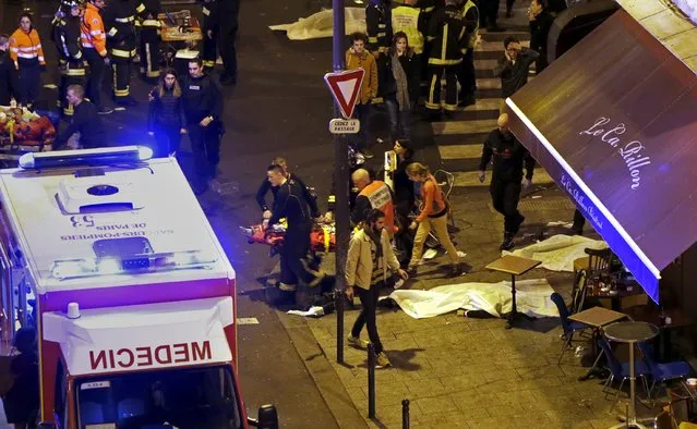 French fire brigade members aid an injured individual near the Bataclan concert hall following fatal shootings in Paris, France, November 13, 2015. (Photo by Christian Hartmann/Reuters)