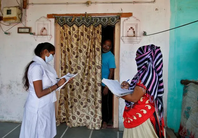 Health workers collect personal data from a man as they prepare a list during a door-to-door survey for the first shot of COVID-19 vaccine for people above 50 years of age and those with comorbidities, in a village on the outskirts of Ahmedabad, India, December 14, 2020. (Photo by Amit Dave/Reuters)