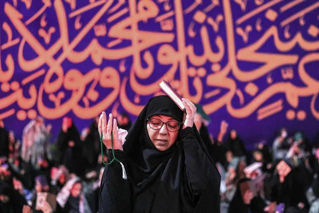 A woman prays during a gathering with other devotees for the ritual prayers for Laylat al-Qadr (Night of Destiny), one of the holiest nights during the Muslim fasting month of Ramadan, outside the Imamzadeh Saleh mosque in Tehran, on April 10, 2023. (Photo by Atta Kenare/AFP Photo)
