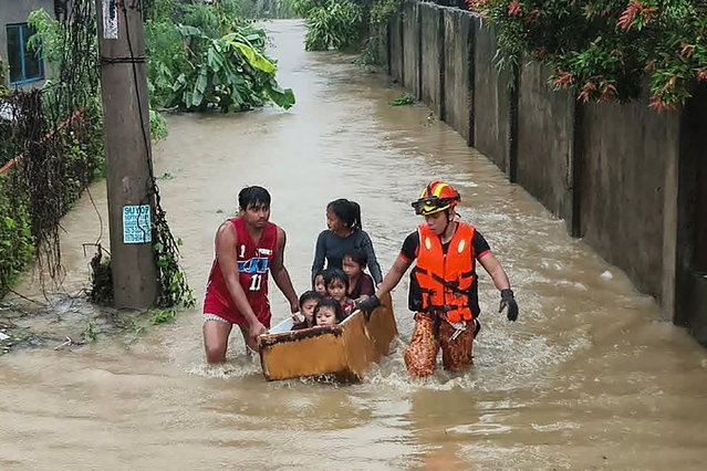 This handout photo taken and released on November 4, 2025 by the Bureau Fire Protection-Toledo City station shows personnel help evacuate people on a makeshift boat made from a discarded refrigerator from their flooded homes following heavy rains brought about by Typhoon Kalmaegi in Toledo City, Cebu province, central Philippines. Residents sought refuge on rooftops and cars floated through flooded streets on November 4 as Typhoon Kalmaegi battered the central Philippines, leaving at least two people dead. (Photo by Handout/Bureau of Fire Protection-Toledo City/AFP Photo)