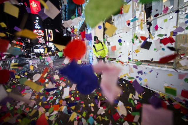 A man uses a blower to clear confetti from the streets after New Year's Eve celebrations in Times Square, New York, January 1, 2015. (Photo by Keith Bedford/Reuters)