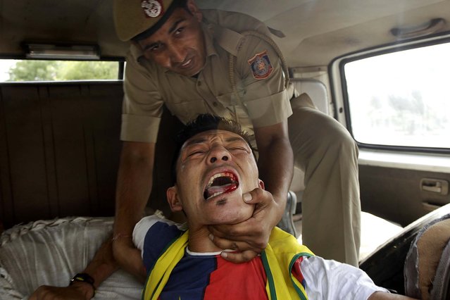 A lone Tibetan protestor, who tried to stage a protest against the visit of Chinese Premier Li Keqiang outside the Chinese embassy, is taken away by police in New Delhi, on May 19, 2013. Just weeks after a tense border standoff, China's new premier headed to India for his first foreign trip as the neighboring giants look to speed up efforts to settle a decades-old boundary dispute and boost economic ties. (Photo by Tsering Topgyal/Associated Press)